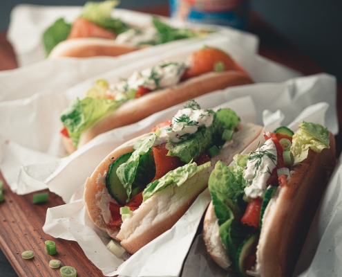 Hotdogs mit Lachs und Meerrettichsoße auf einem Holzbrett