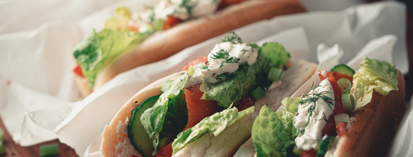 Hotdogs mit Lachs und Meerrettichsoße auf einem Holzbrett