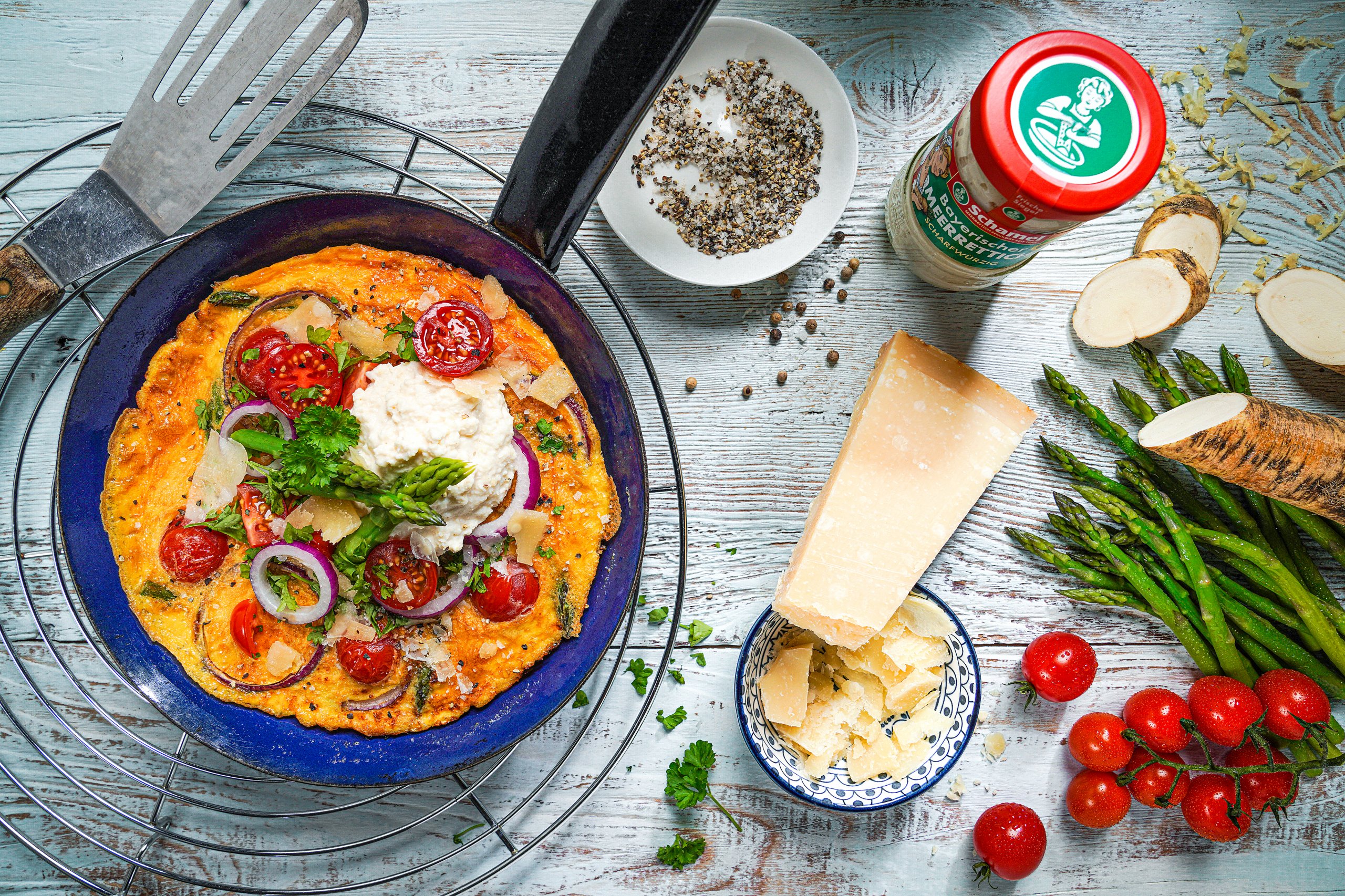 Pfanne mit Omelett mit grünem Spargel, Tomaten und Meerrettich